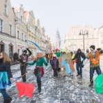 korowód fundacji dom 2017 uczestnicy przechodząc po rynku machają kolorowymi flagami